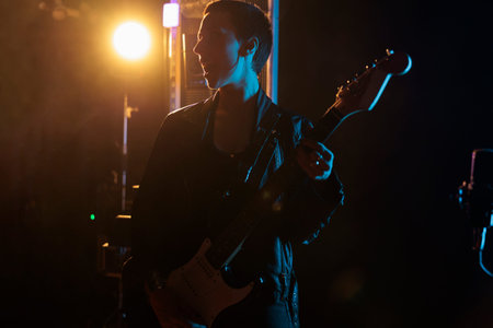Rockstar woman with leather jacket holding electric guitar while performing heavy metal song,...
