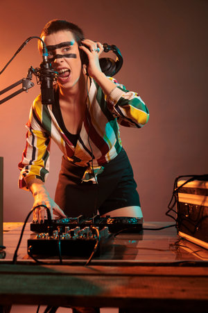 Musical performer mixing music at dj turntables, playing techno sounds with mixer and bass key in...
