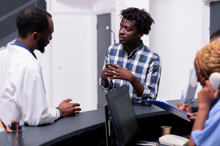 African american patient and doctor talking about disease diagnosis at hospital reception counter....