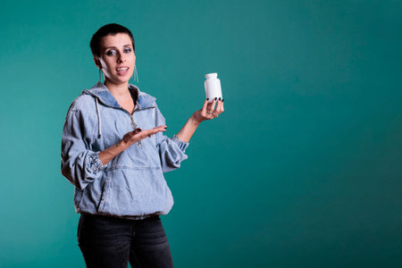 Portrait of woman holding pills bottle showing at camera after receiving treatment recovery on prescription. Smiling adult reviewing pharmaceutical supplement, healthy lifestyle conceptの写真素材