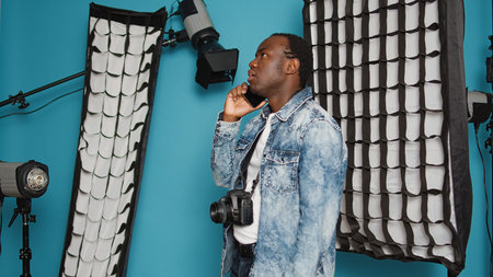 African american model talking on smartphone call over background with photography equipment and...