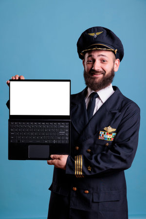Smiling airplane aviator showing laptop with empty white screen, aviation academy software...