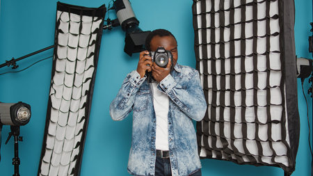 Male photographer using dslr camera and lens to take pictures in studio backstage, capturing photos...