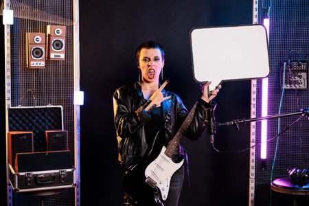 Musician showing blank placard with copy space for advertisement in music studio, person playing...