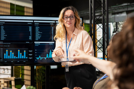 Determined team of professional women assembling to review charts and data projections, illustrating...