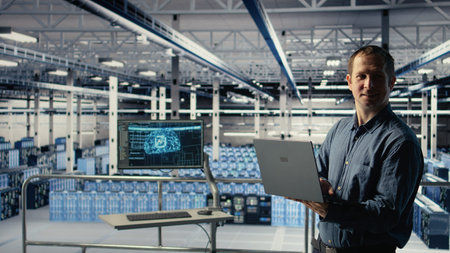 Engineer in data center checks AI dashboard using laptop during routine systems review. IT expert...