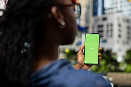 Green screen smartphone used by young girl on park bench relaxing by looking at social media posts...
