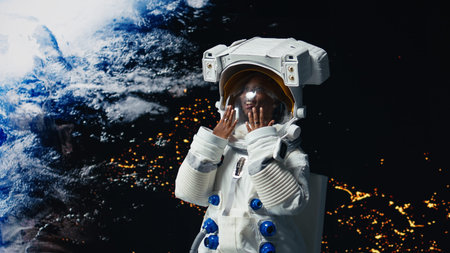 Excited astronaut prepares to land on Earth after finishing planetary expedition. Jolly african american cosmonaut in high tech suit finishing deep space mission with starship, retuning home, camera Aの写真素材