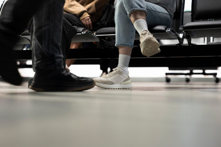 Close up of passengers legs sitting in waiting area at bus station, waiting for their metropolitan urban transit bus. Weekday mobility and everyday travel around town, public transportation.