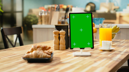 Vertical mockup screen on tablet in empty rustic kitchen with natural light, breakfast table and rustic furniture in apartment. No people in open space with appliances and kitchenware.