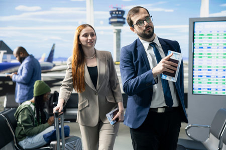 Corporate delegation members discussing itinerary in airport terminal lounge, preparing for overseas global business summit. Team with suitcases prepare for business trip together.