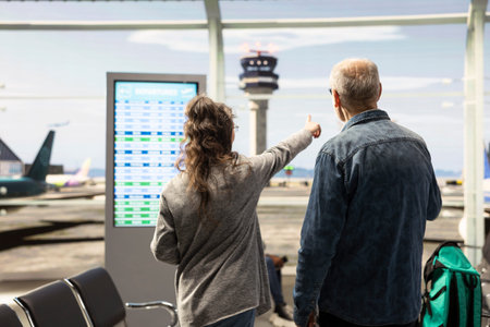 Active retirees with luggage walking through airport terminal, excited for vacation and sightseeing adventure. Elderly couple representing freedom and breaking stereotypes about aging.