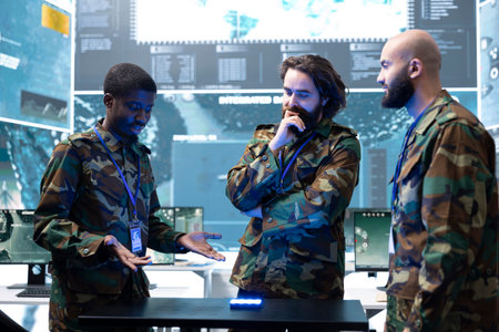 Military specialist explains holographic battlefield projection to team colleagues. Army personnel reviewing tactical strategy using AR technology, coordinating next operation