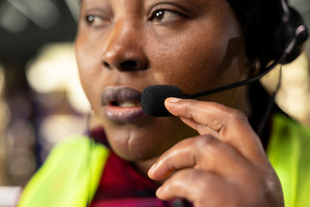 Close up of black worker using headset to provide package tracking status for cargo updates. Woman monitoring airway bill numbers and barcodes for order fulfillment, express delivery.
