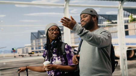 Smiling friends chatting in airport, holding takeaway coffee cup. Relaxed African american passengers in modern airport terminal talking, drinking beverage