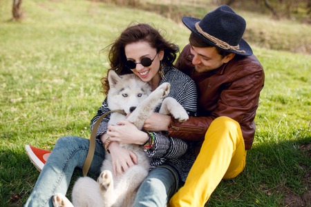Active young couple playing with their dog in a sunny day. Horizontal outside shot.の写真素材