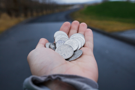 A lot of coins in the palm of the hand of traveler man on road background. Financial concept.の写真素材