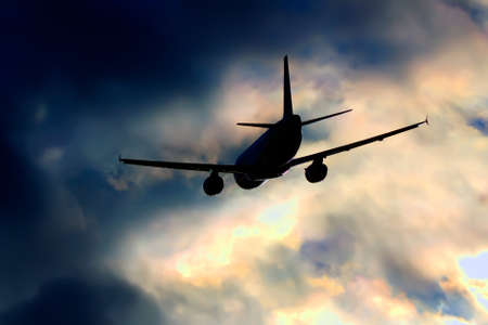 Plane flying into the stormy sunset cloudsの写真素材
