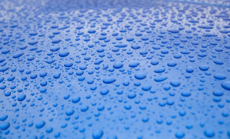 Rain drops on blue metallic surfaceの写真素材