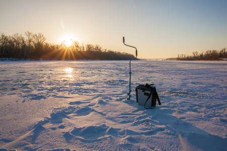 Ice fishing scene - sunrise on the riverの写真素材