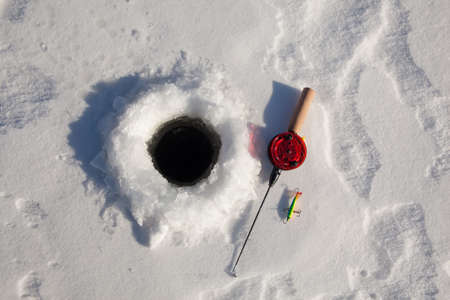 Ice fishing rod with the lure by the holeの写真素材
