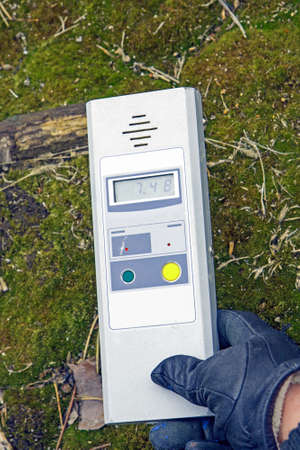Man checking the level of radiation on the ground with a portable radiometerの写真素材