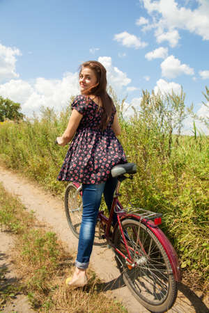 Smiling girl riding her bike in the field in summertimeの写真素材
