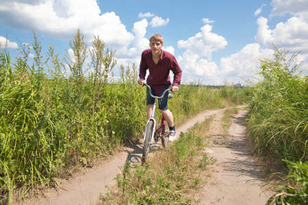 Young man riding the bike in the fieldの写真素材