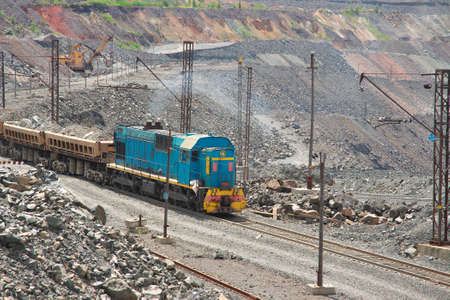 Cargo train carrying iron ore on the opencast mining quarry