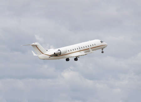 Business jet taking off to the cloudy skyの写真素材