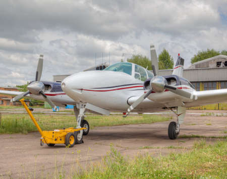 Private twin-engine propeller plane on a small airfield with stormy clouds on the background