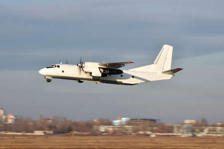White turboprop cargo plane takes off on sunset with cloudy sky on the backgroundの写真素材