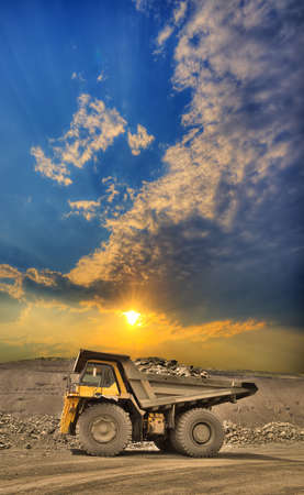 Heavy mining truck loaded with iron ore on the opencast with beautiful sunsetの写真素材
