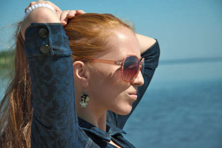 Portrait of a pretty red haired girl by the seaの写真素材