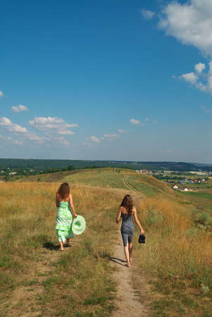 Two barefooted girls walking down the hill along the pathの写真素材