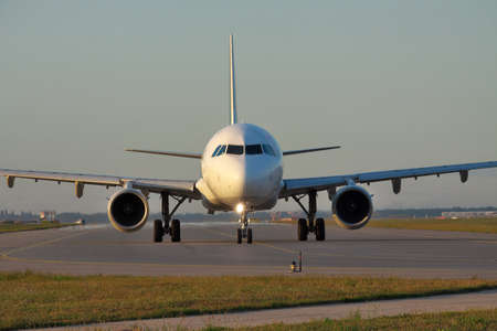 Passenger jet plane taxiing along the runway on sunsetの写真素材
