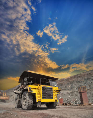 Mining truck loaded withiron ore driving along the opencast on sunsetの写真素材