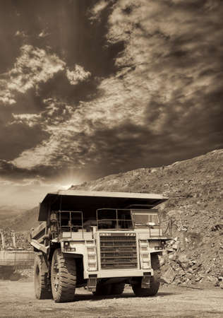 Heavy dump truck transporting iron ore from the opencast on sunset - black and white imageの写真素材