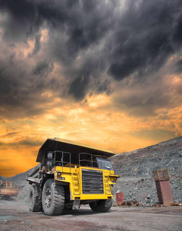 Mining truck loaded withiron ore driving along the opencast on stormy sunsetの写真素材