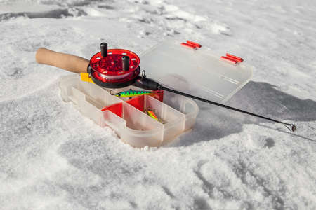 Ice fishing rod and box with lures on the snow