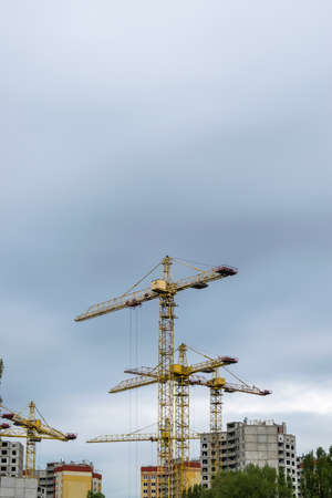 Several construction cranes developing the buildings on a cloudy day