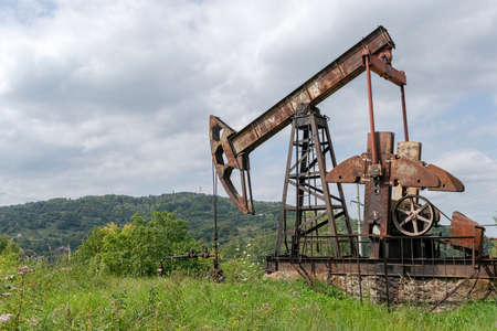 Oil rig is pumping the oil with beautiful landscape on the backgroundの写真素材