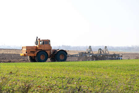 Tractor cultivating the field on the autumn dayの写真素材