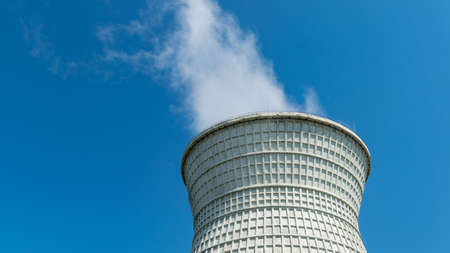 Cooling tower of the power plant with some steam on it against blue sky backgroundの写真素材