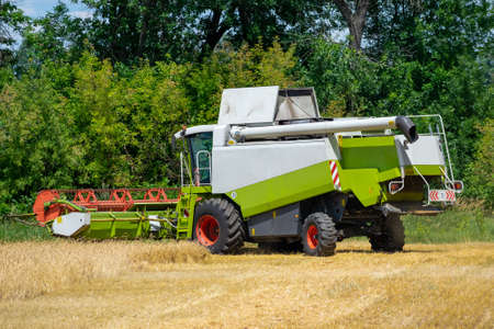 Harvester at work on the field harvesting ripe wheatの写真素材
