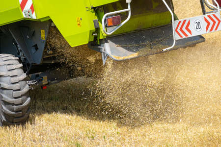 Harvester at work on the field harvesting ripe wheatの写真素材
