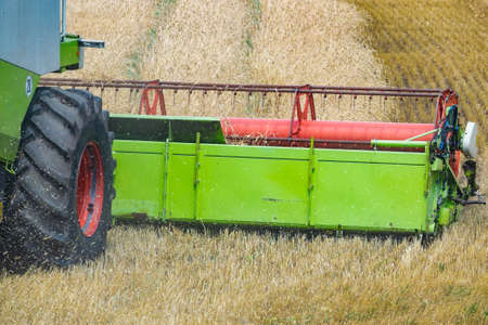 Harvester at work on the field harvesting ripe wheat