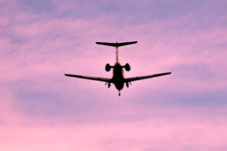 Business jet is landing on sunset or sunrise silhouetteの写真素材