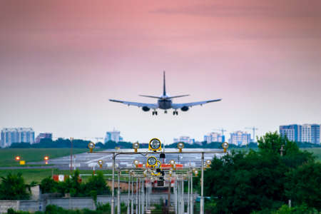 Passenger plane landing on sunset or sunrise in the airport with the approach light in frontの写真素材