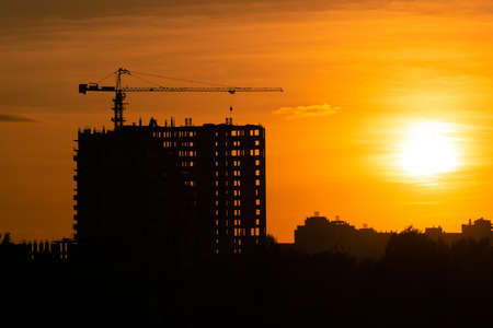 Construction crane developing the building on sunsetの写真素材